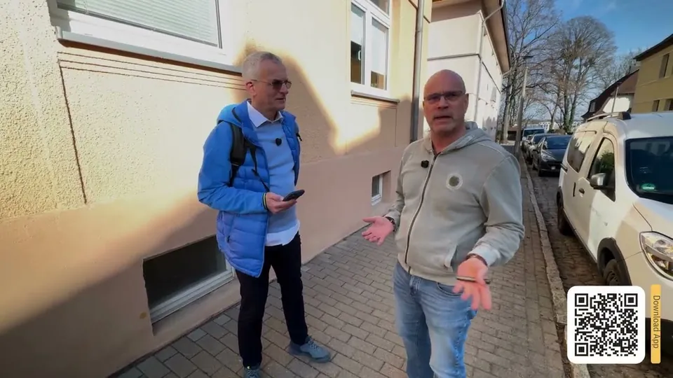 Martin Dierksen und Makler Thomas Franck vor einem Wohnhaus, einer hält ein iPhone