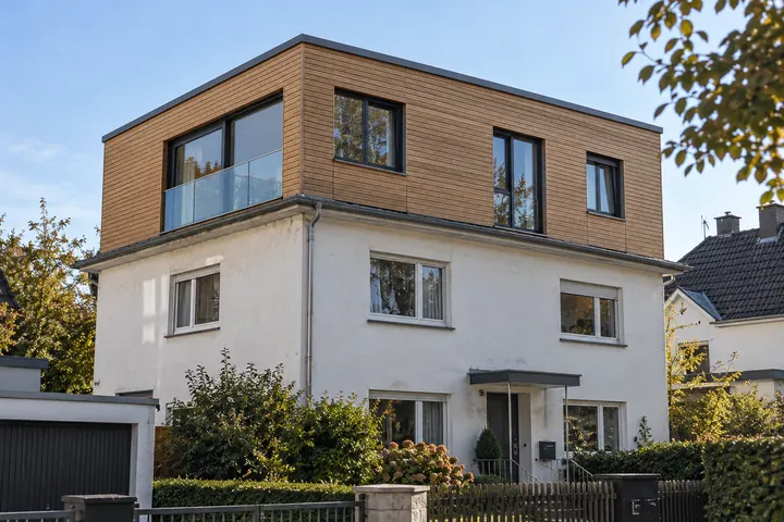 Zweigeschossiges Putzhaus mit aufgesetztem Holzgeschoss und Flachdach