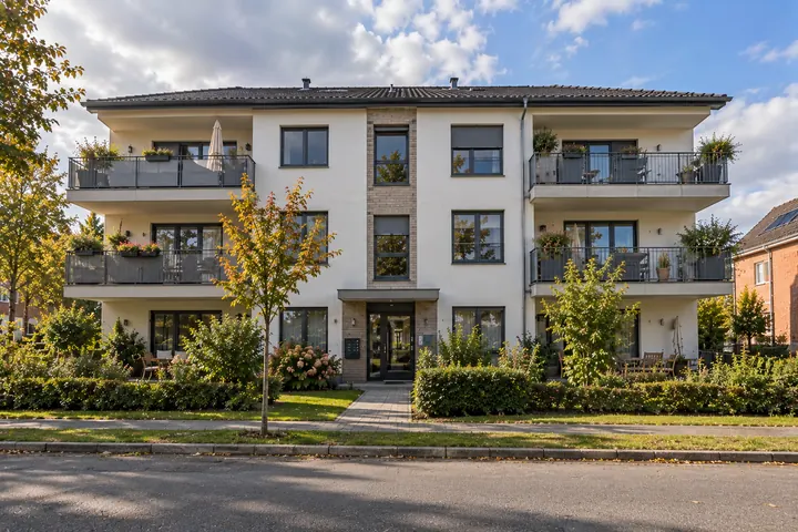 Dreigeschossiges Mehrfamilienhaus mit Balkonen und begrüntem Vorgarten